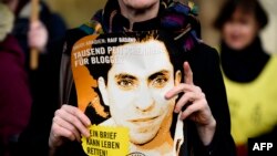 Seorang aktivis kelompok HAM 'Amnesty International' membawa foto blogger Saudi Raif Badawi dalam protes menuntut pembebasan Badawi di depan Kedubes Saudi di Berlin, Jerman (foto: dok).