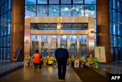 FILE - A man bowing in front of flowers and a photo of the late ophthalmologist Li Wenliang outside the Houhu Branch of Wuhan Central Hospital in Wuhan in China's central Hubei province, Feb. 7, 2020.