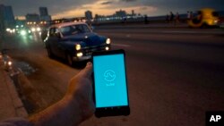 A man holds his phone showing the app "Sube," a ride-hailing app for the aging American sedans on the streets of Havana, in Havana, Cuba, Feb. 21, 2019.