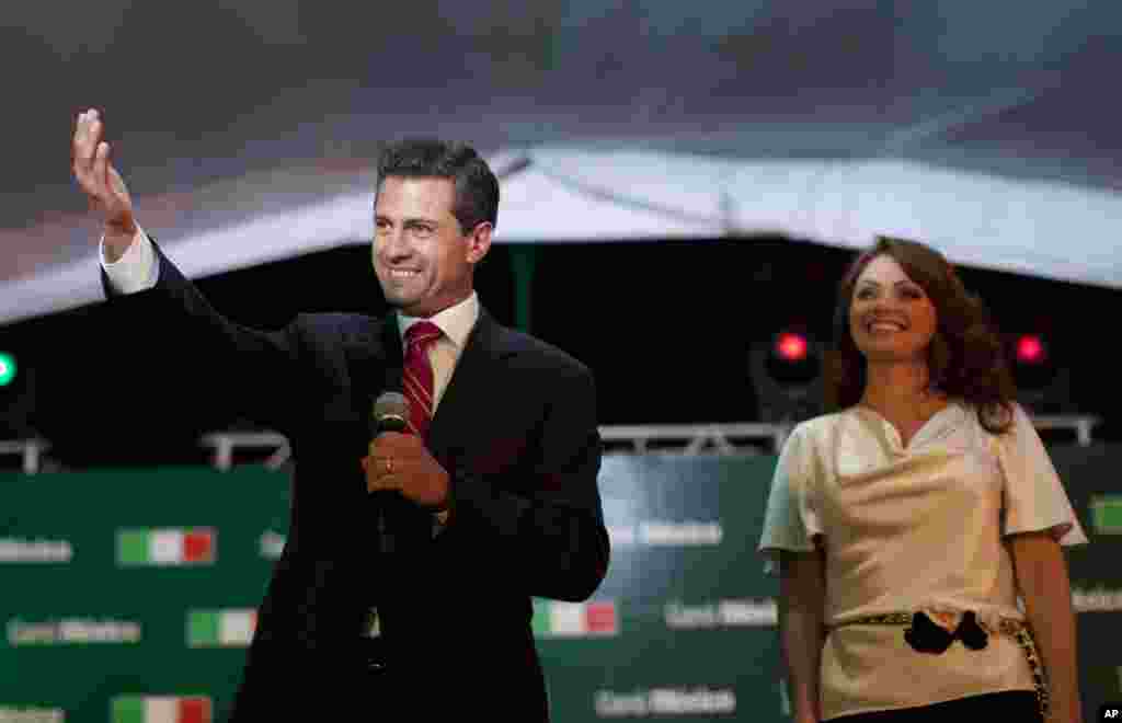 Enrique Pena Nieto, presidential candidate for the Revolutionary Institutional Party (PRI), left, speaks to supporters accompanied by his wife Angelica Rivera at the party's headquarters in Mexico City, early Monday, July 2, 2012. 