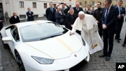 El papa Francisco pone su autógrafo en el Lamborghini donado y que será subastado para reconstruir comunidades cristianas de Irak devastadas por ISIS.