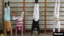 FILE - Members of the Nanjing children diving team practise standing on their hands during a training session at a sports college in Nanjing, Jiangsu province, Jan. 13, 2008. 