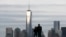 FILE - A couple look out at New York's Lower Manhattan and One World Trade Center from Liberty State Park in Jersey City, New Jersey.