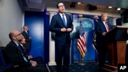 President Donald Trump listens as Treasury Secretary Steven Mnuchin speaks at a news conference in the James Brady Press Briefing Room at the White House, Aug. 10, 2020, in Washington.