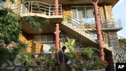 A man waters flowers outside a luxury house in the city of Kabul, Afghanistan, Sept. 29, 2024. (AP Photo/Siddiqullah Alizai)