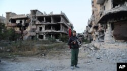 FILE - A civilian fighter holding the Libyan flag stands in front of damaged buildings in Benghazi, Libya, Feb. 23, 2016.