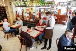 An employee, wearing a protective face mask, serves customers during the reopening of the hall of the Mesturet restaurant amid the coronavirus disease (COVID-19) in Paris, June 15, 2020.