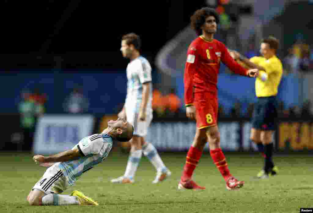 Argentina's players celebrate near Belgium's Marouane Fellaini, left, after winning their 2014 World Cup quarter-finals, Brasilia national stadium, July 5, 2014.