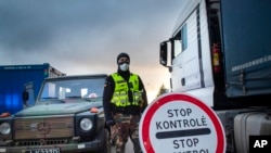 A Lithuanian border guard stands next to trucks stuck in traffic jams for 60 kilometers (36 miles) on Lithuanian side to enter Poland through Kalvarija-Budzisko check point, 230 km (144 miles) west of Vilnius, Lithuania.