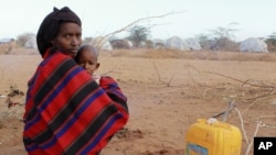 FILE - A refugee woman and her child from Somalia sit in the open as they camp with their belongings outside Ifo refugee camp in Dadaab, near the Kenya-Somalia border, July 30, 2011.