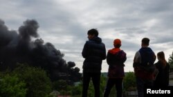 Підлітки дивляться на дим, який здіймається після російського ракетного удару по Харкову, 17 травня 2024 року. Фото REUTERS