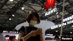 A visitor checks a mobile phone near the Huawei logo during the Mobile World Congress in Shanghai, China June 28, 2023.