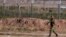 FILE - A Turkish soldier walks by the border fence with Syria.
