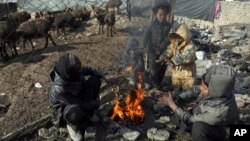 FILE - Afghan boys warm themselves near a bonfire on the cold day in a poor neighborhood on the outskirts of Kabul, Afghanistan, Dec. 17, 2017.