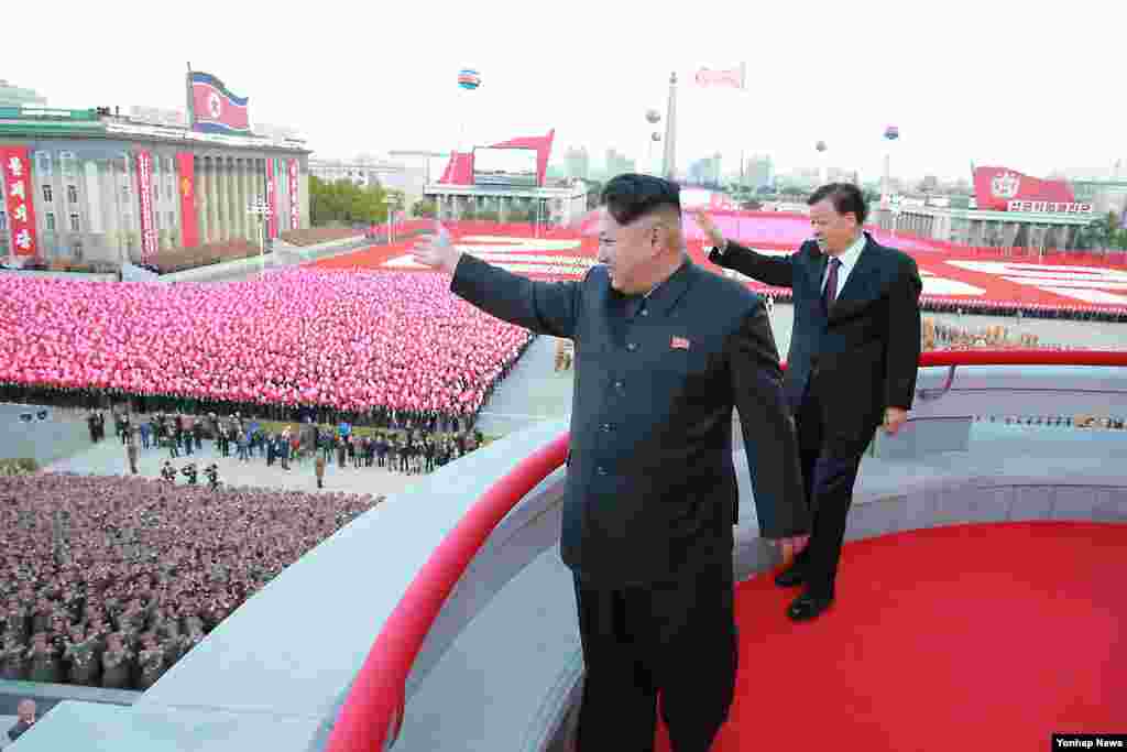 朝鲜领导人金正恩同中共政治局常委同刘云山在平壤的朝鲜&quot;劳动党&quot;建党70周年阅兵式上招手（2015年10月10日）。