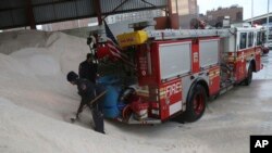 Petugas pemadam kebakaran di New York mengisi garam ke dalam wadah di truk mereka yang akan digunakan untuk mencairkan es (8/2). (AP/Mary Altaffer)