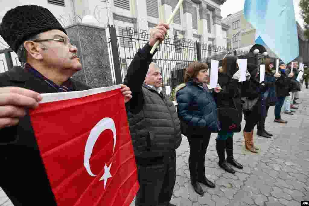 A Crimean Tatar holds a Turkish flag as he takes part in a demonstration by Crimean Tatars, in front of the Russian embassy in Kyiv, Urkaine. Protesters demanded an end to political repression by Russian security forces against the Tatars on the Crimean peninsula, which was captured by Russia in 2014.