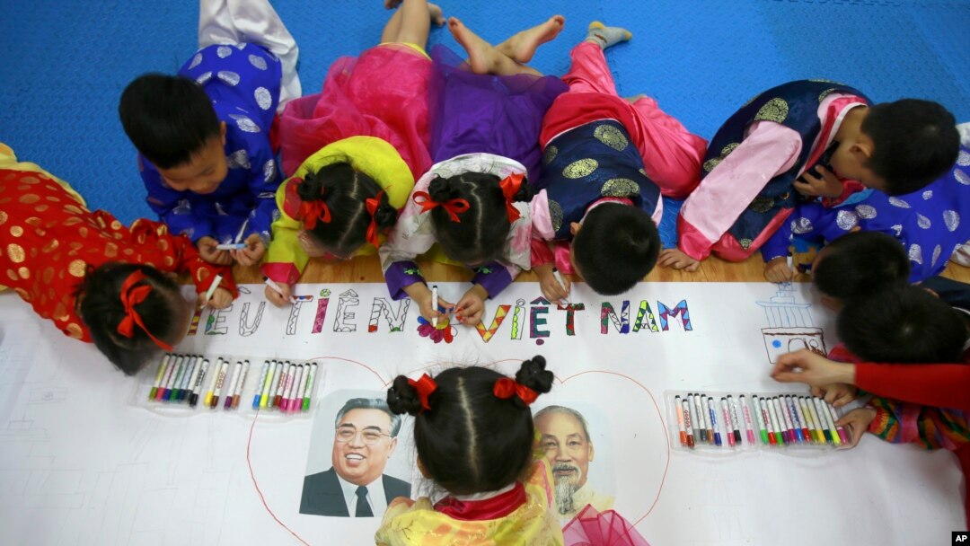 Anak-anak mengenakan baju tradisional Vietnam dan Korea sedang mewarnai poster dengan potret mendiang pemimpin revolusi Vietnam, Ho Chi Minh (kanan) dan mendiang pemimpin Korea Utara Kim Il Sung di TK Persahabatan Vietnam-Korea di Hanoi, Vietnam, 21 Februari 2019.