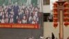 Residents walk past a propaganda board showing Chinese President Xi Jinping with local children and slogans calling for unity amongst the different ethnicities in Shule county in Xinjiang Uyghur Autonomous Region on March 20, 2021. (Ng Han Guan/AP)