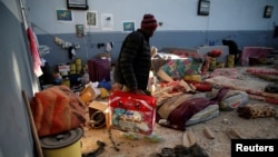FILE - A migrant carries his belongings at a detention center for mainly African migrants, that was hit by an airstrike in the Tajoura suburb of Tripoli, Libya, July 3, 2019.
