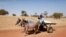 FILE - Malian children ride on a donkey cart on the road between Timbuktu and Douentza.