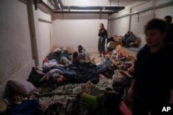 People shelter from Russian artillery shelling in a school basement in the village of Horenka close to Kyiv, Ukraine, Sunday, March 6, 2022. (AP Photo/Efrem Lukatsky, File)