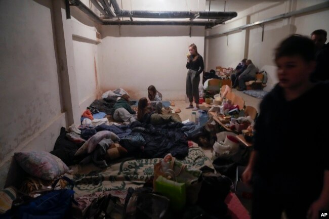 People shelter from Russian artillery shelling in a school basement in the village of Horenka close to Kyiv, Ukraine, Sunday, March 6, 2022. (AP Photo/Efrem Lukatsky, File)