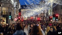 Shoppers wear face masks as they walk in Regent Street, ahead of the new Tier-4 restriction measures, in London, Saturday, Dec. 19, 2020. Britain's Prime Minister Boris Johnson says Christmas gatherings cannot go ahead and non-essential shops must…