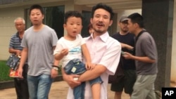 This image taken from video shows Chinese labor activists Hua Haifeng, center, carrying his son Bobo, and Li Zhao, second from left, leave a police station after being released in Ganzhou in southern China's Jiangxi Province, June 28, 2017.