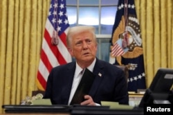 FILE - U.S. President Donald Trump signs documents as he issues executive orders in the Oval Office at the White House in Washington, Jan. 20, 2025.