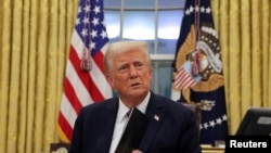 US President Donald Trump signs documents as he issues executive orders and pardons for Jan. 6 defendants in the Oval Office at the White House in Washington, Jan. 20, 2025.