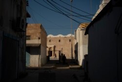 FILE - People walk outside a mosque in Tripoli, Libya, on Feb. 27, 2020. Eastern-based opposition forces attacked Tripoli last spring to wrest it from control of the weak U.N.-backed government. The fierce fighting has killed hundreds of civilians.