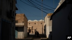 FILE: People walk outside a mosque in Tripoli, Libya, on Feb. 27, 2020. Islam is Libya's state religion, and Christianity is barred from trying to convert Muslims.