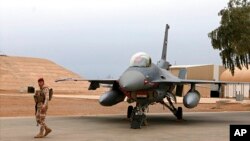 Seorang tentara irak berjaga dekat sebuah pesawat jet tempur F-16 di Pangkalan Udara Balad, Irak, 13 Februari 2018. Pada Minggu, 18 April 2021, lima roket menghantam pangkalan itu. (Foto: AP/arsip)