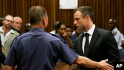 Atlet Afrika Selatan Oscar Pistorius (kanan) dibawa keluar ruang sidang di Pretoria (21/10). (AP/Themba Hadebe)