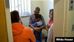 El presidente Obama conforta a su hija menor Sasha, durante la visita a la celda de Mandela en la Isla Robben, junto a su hija Malia y la primera dama Michelle Obama.