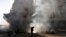 A man walks in front of a burning building after a Syrian Air force air strike in the Ain Tarma neighborhood of Damascus January 27, 2013. 