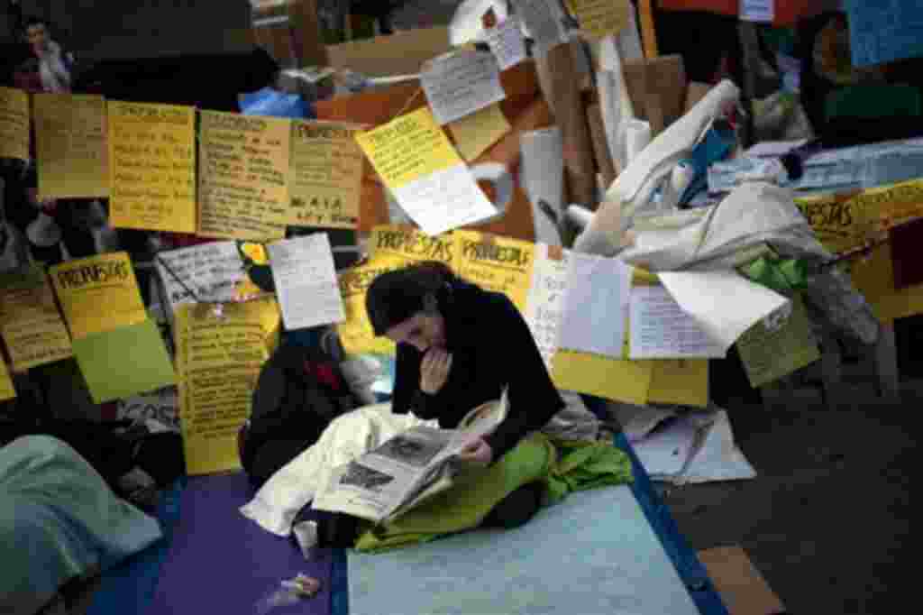 Una manifestante lee el periódico mientras se pasa la noche en la plaza de Sol, durante una protesta en Madrid, 20 de mayo de 2011.