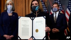 Ketua DPR AS Nancy Pelosi menunjukkan naskah pasal pemakzulan terhadap Presiden Donald Trump sebelum melimpahkan kasus tersebut ke Senat untuk disidangkan di Capitol Hill, Washington, 13 Januari 2021.