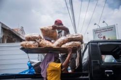 Seorang buruh membawa barang di atas kepalanya di sebuah pasar di Surabaya pada Hari Perempuan Internasional, 8 Maret 2021. (Foto: AFP/Juni Kriswanto)