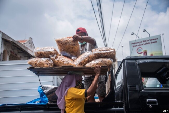 Seorang buruh membawa barang di atas kepalanya di sebuah pasar di Surabaya pada Hari Perempuan Internasional, 8 Maret 2021. (Foto: AFP/Juni Kriswanto)