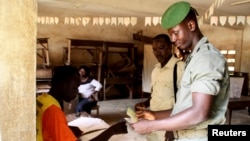 A Togolese soldier has his identity checked before casting his ballot during the early voting for the country's parliamentary elections, at the RIT camp in Lome, July 22, 2013.