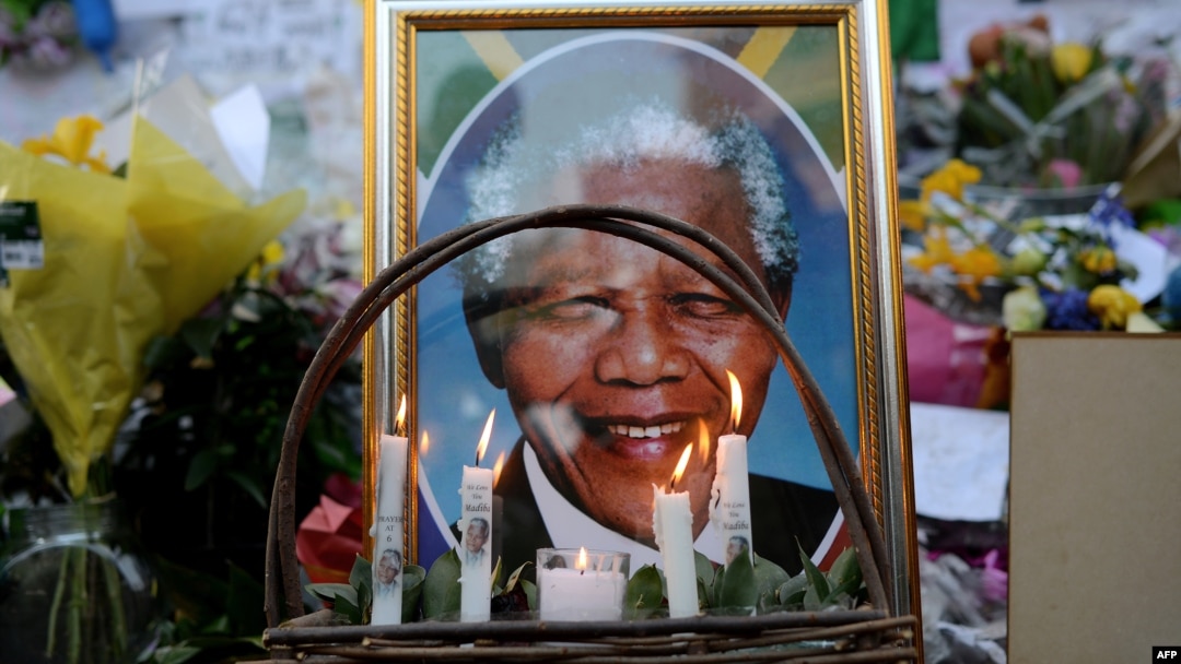 FILE - Candles are seen burning by a portrait of Nelson Mandela outside of the Mediclinic Heart Hospital in Pretoria, South Africa, where he was in critical condition, July 6, 2013. 