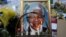 Candles burn in front of a portrait of Nelson Mandela outside of the Mediclinic Heart hospital in Pretoria on July 6, 2013.