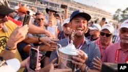 Bryson DeChambeau celebrates with fans and the trophy after winning the U.S. Open golf tournament June 16, 2024, in Pinehurst, N.C.