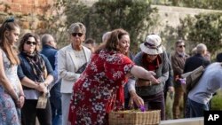 Gaye Myler (tengah, melempar sekuntum bunga ke kolam refleksi di Port Arthur, Australia, Rabu, 28 April 2021, dalam peringatan 25 tahun pembantaian massal di negara bagian Tasmania. (Luke Bowden/Pool via AP)