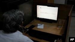 A Pakistani man waits while trying to open a page on a desktop computer as the internet continues to run slowly, in Lahore, Pakistan, on Aug. 19, 2024.