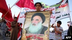 Một người đàn ông Iraq đem theo bức chân dung Đại giáo sĩ Ayatollah Ali al-Sistani, lãnh đạo tinh thần của người Shia, khi người dân tập trung bày tỏ quyết tâm xin tham gia lực lượng an ninh Iraq trong cuộc chiến chống các phần tử chủ chiến Jihad, 19/6/2014