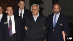 Tổng Giám đốc IMF Dominique Strauss-Kahn (giữa) bị còng và áp tải ra khỏi Trụ sở cảnh sát ở New York ngày 15 /5/2011