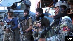 Afghan security force personnel stand along the roadside in Herat on Aug. 12, 2021, as Taliban fighters took over the police headquarters in Herat,